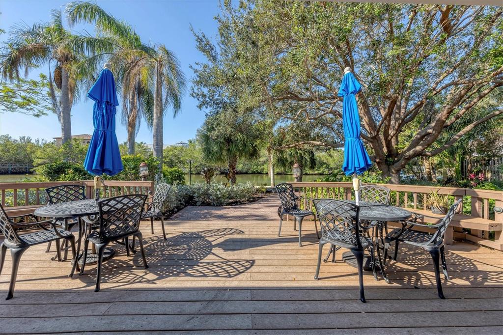 9393 Midnight Pass Road, Unit 302 Sarasota, FL 34242 - Photo 53 of 65 a view of a patio with table and chairs potted plants and palm tree