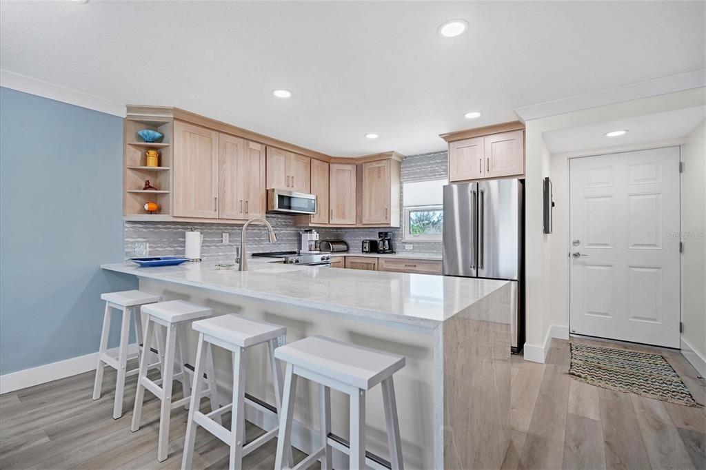 9393 Midnight Pass Road, Unit 302 Sarasota, FL 34242 - Photo 8 of 65 a kitchen with stainless steel appliances granite countertop a refrigerator a stove a sink and white cabinets with wooden floor