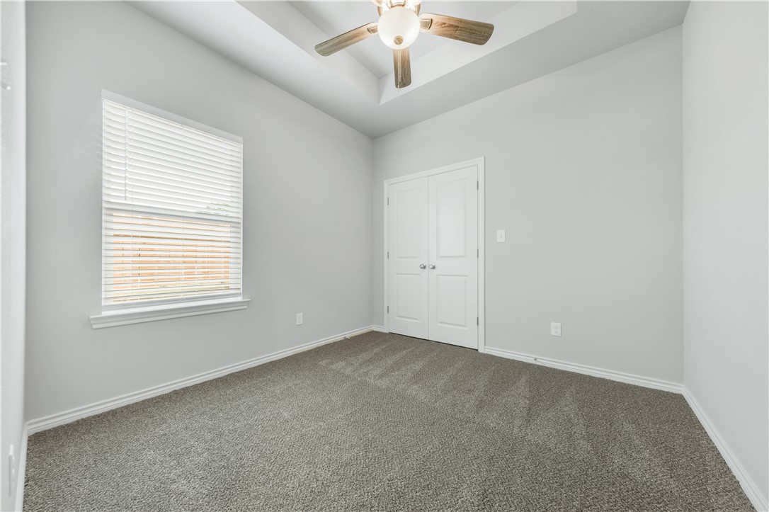 1805 Pin Oak Street Bryan, TX 77803 - Photo 17 of 20 Unfurnished bedroom featuring dark colored carpet, a closet, a ceiling fan, and a raised ceiling