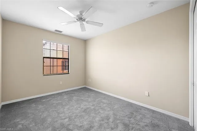 an empty room with windows and ceiling fan