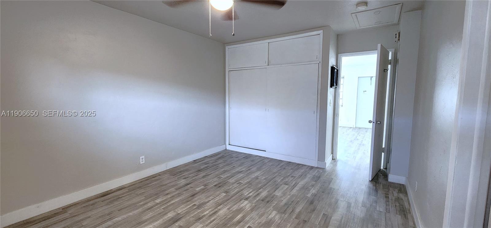 2901 Polk Street, Unit 14 Hollywood, FL 33020 - Photo 11 of 16 an empty room with wooden floor a chandelier fan and windows