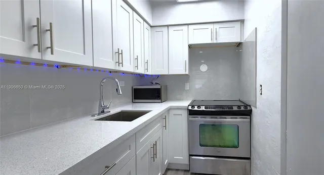 a kitchen with granite countertop a sink a stove and cabinets