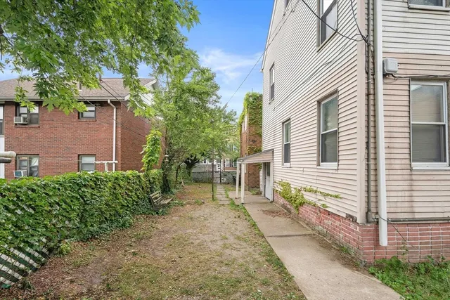 a backyard of a house with table and chairs and potted plants
