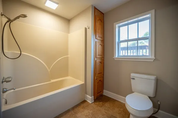 an empty room with wooden floor closet and windows