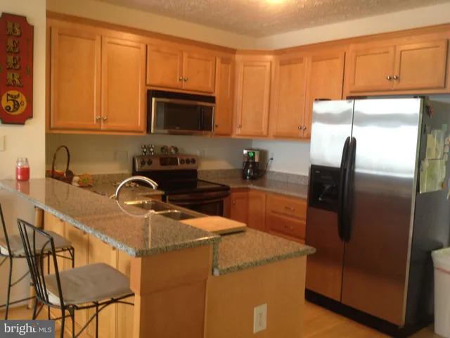 a kitchen with stainless steel appliances granite countertop a refrigerator a sink a stove and cabinets