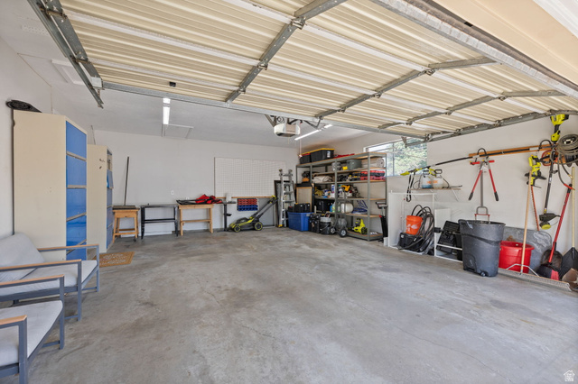 2370 Quail Run Circle East Sandy, UT 84093 - Photo 35 of 54 Spacious 2-car garage featuring a concrete floor, built-in shelving, and ample overhead lighting