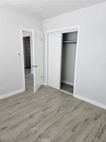 a view of an empty room with wooden floor and closet