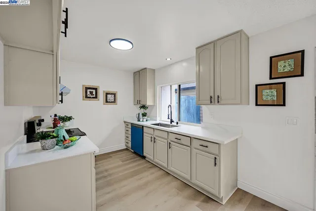 a kitchen with white cabinets and sink