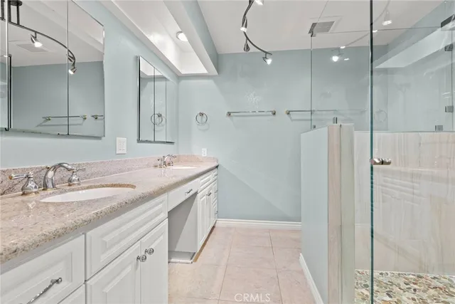 a bathroom with a granite countertop sink two mirror and shower