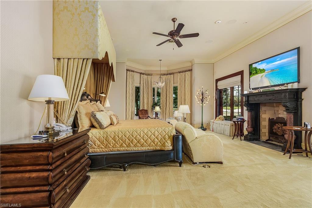 14928 Celle Way Naples, FL 34110 - Photo 29 of 35 a bedroom with a bed a lamp on the floor and a flat tv screen