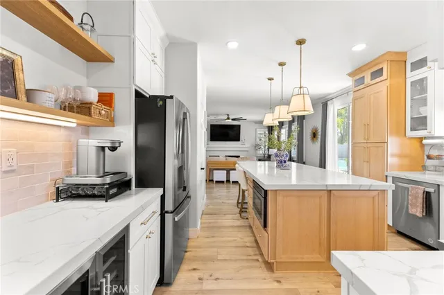 a kitchen with stainless steel appliances kitchen island granite countertop a refrigerator a stove and a sink with wooden floor