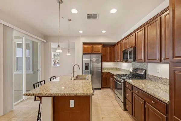 a kitchen with stainless steel appliances granite countertop a sink a stove and a wooden cabinets