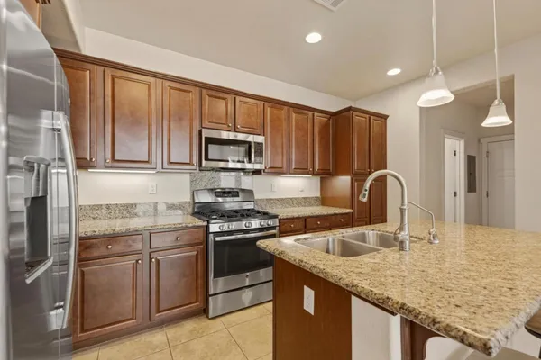 a kitchen with stainless steel appliances granite countertop a sink stove refrigerator and cabinets