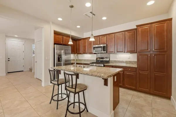 a kitchen with kitchen island granite countertop wooden cabinets and a refrigerator