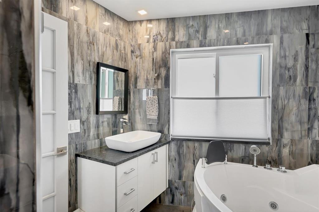 7985 Manasota Key Road Englewood, FL 34223 - Photo 29 of 83 a bathroom with a sink a mirror and a bathtub