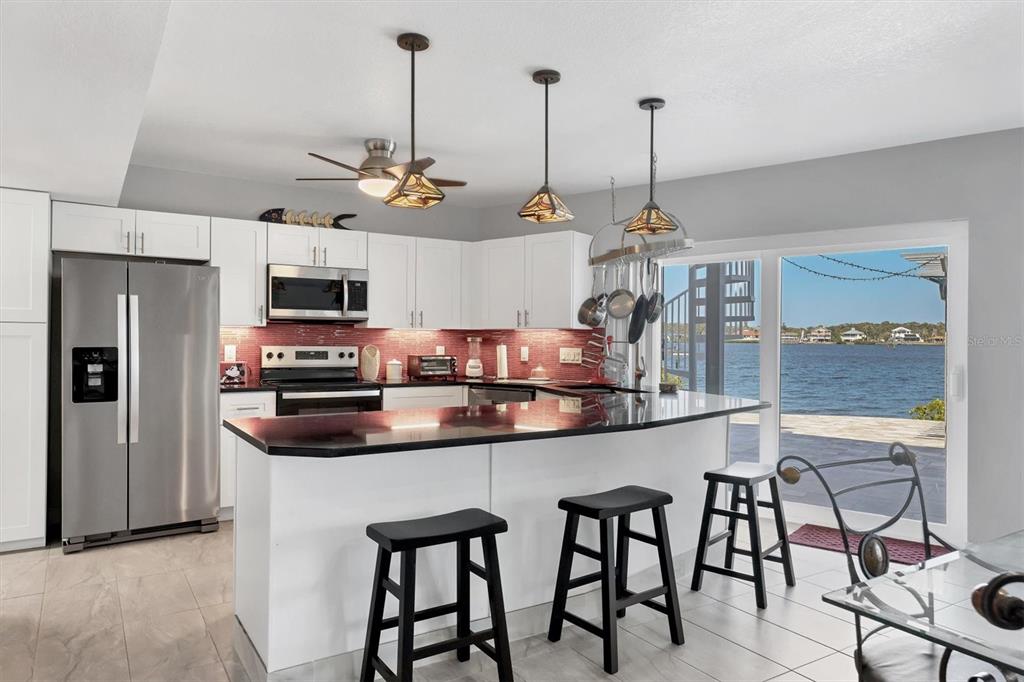 7985 Manasota Key Road Englewood, FL 34223 - Photo 43 of 83 a kitchen with stainless steel appliances granite countertop a sink a counter and chairs