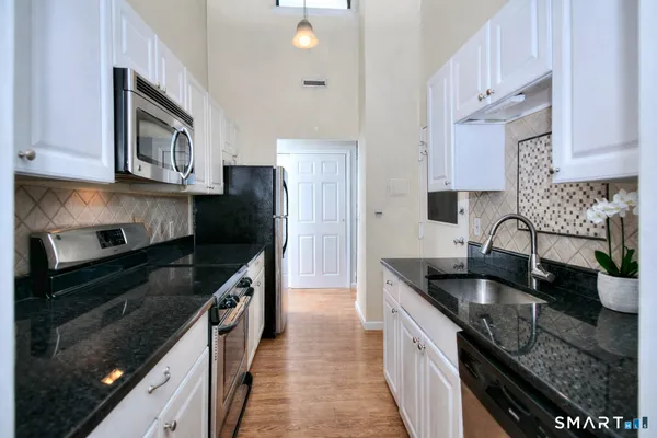 a kitchen with granite countertop stainless steel appliances a sink stove top oven and cabinets