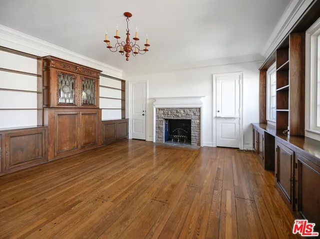 a view of an empty room with wooden floor fireplace and a window