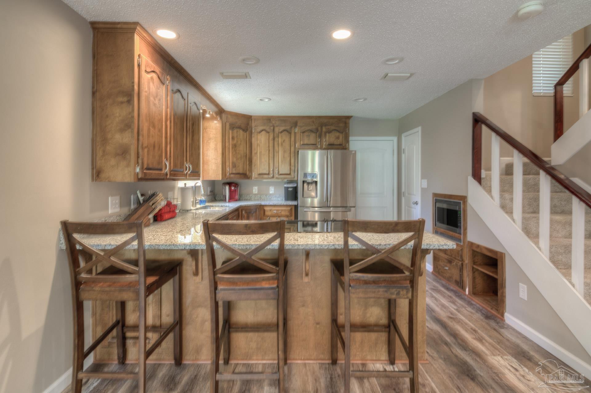 4917 Shell Road Milton, FL 32570 - Photo 11 of 49 a kitchen with stainless steel appliances kitchen island granite countertop a table chairs sink and cabinets