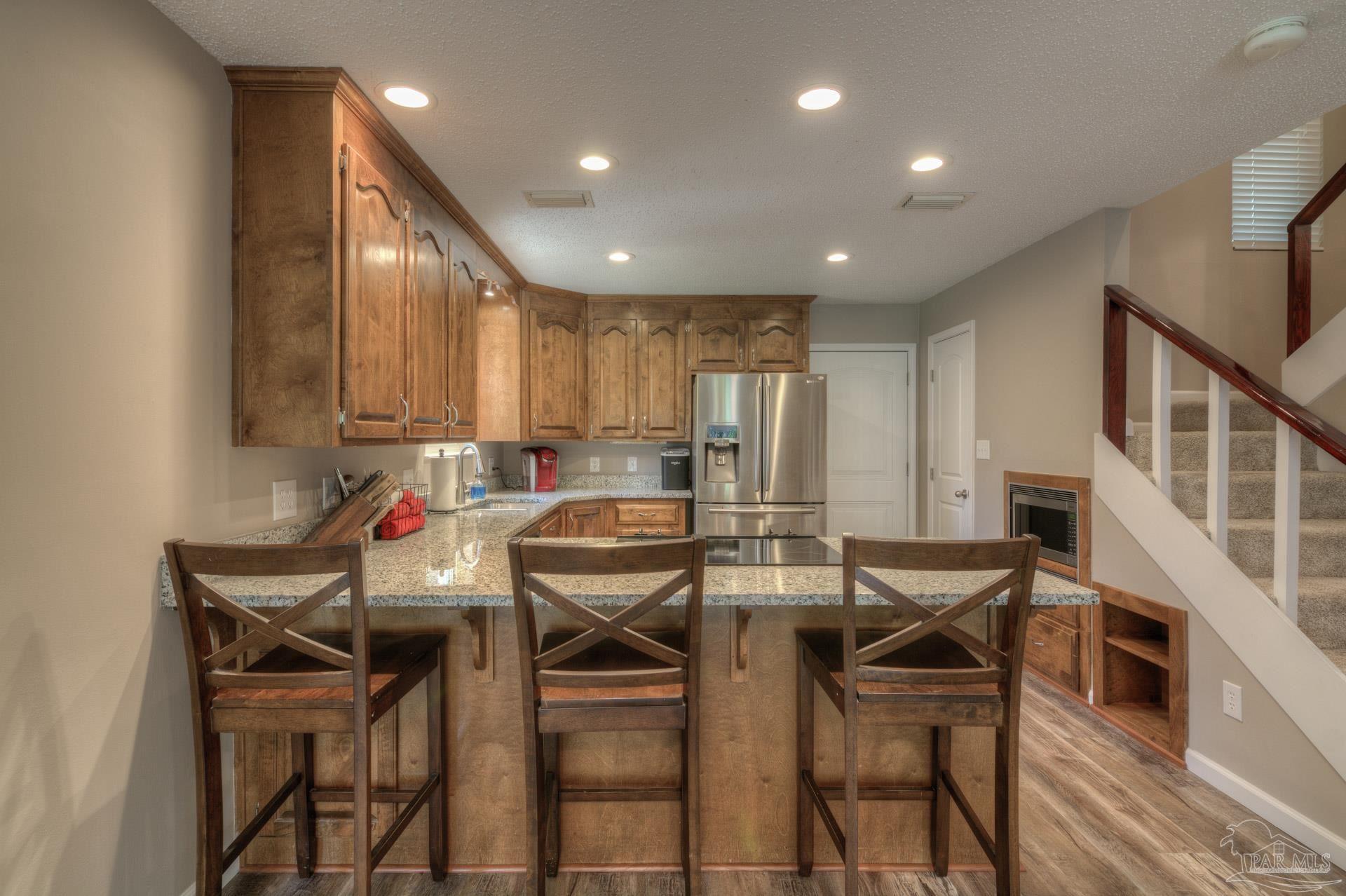 4917 Shell Road Milton, FL 32570 - Photo 12 of 49 a kitchen with stainless steel appliances kitchen island granite countertop a dining table chairs and white cabinets