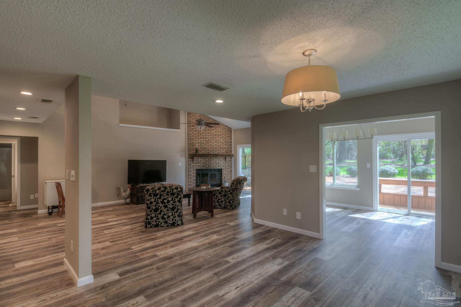 4917 Shell Road Milton, FL 32570 - Photo 16 of 49 a view of a livingroom with furniture a fireplace wooden floor and chandelier