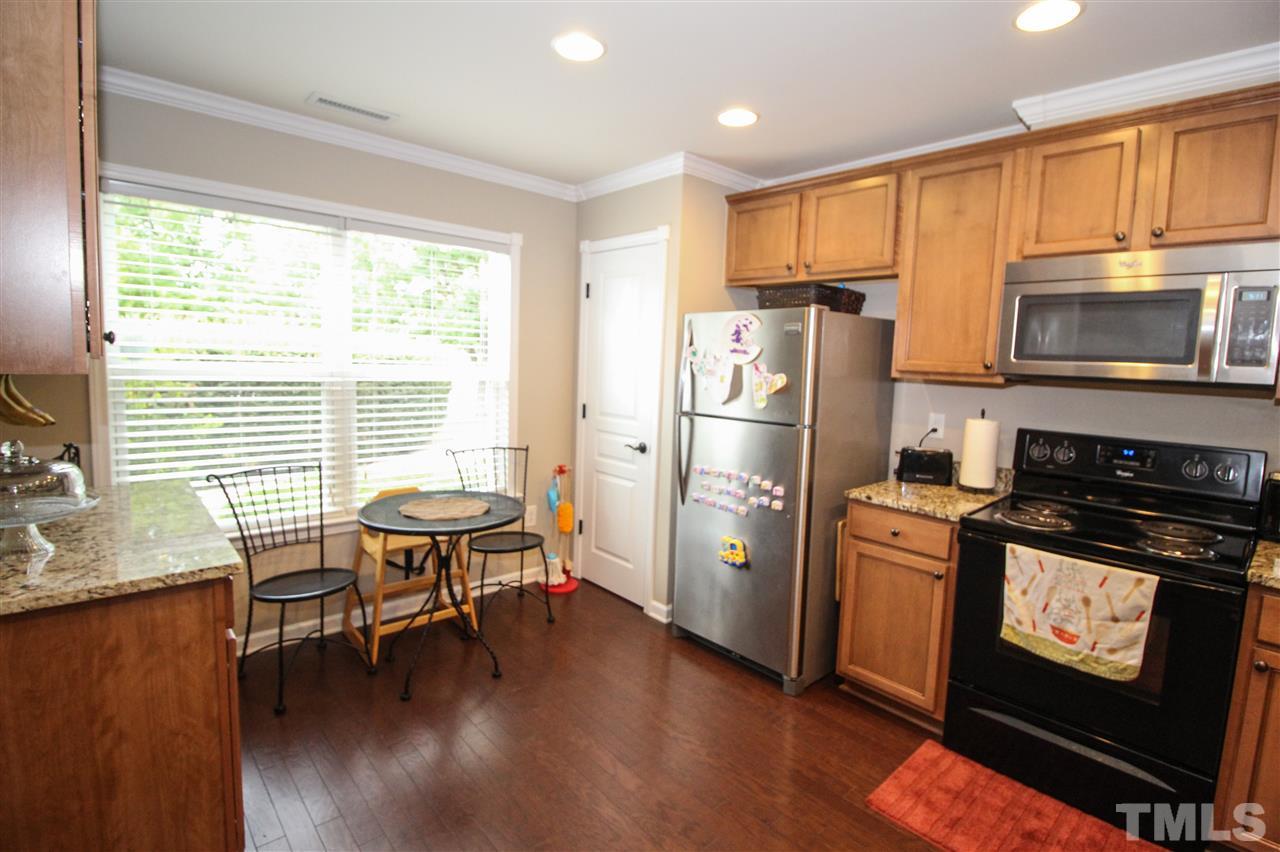 2901 Berkeley Springs Place Raleigh, NC 27616 - Photo 5 of 24 a kitchen with stainless steel appliances granite countertop a stove a refrigerator a sink a dining table and chairs