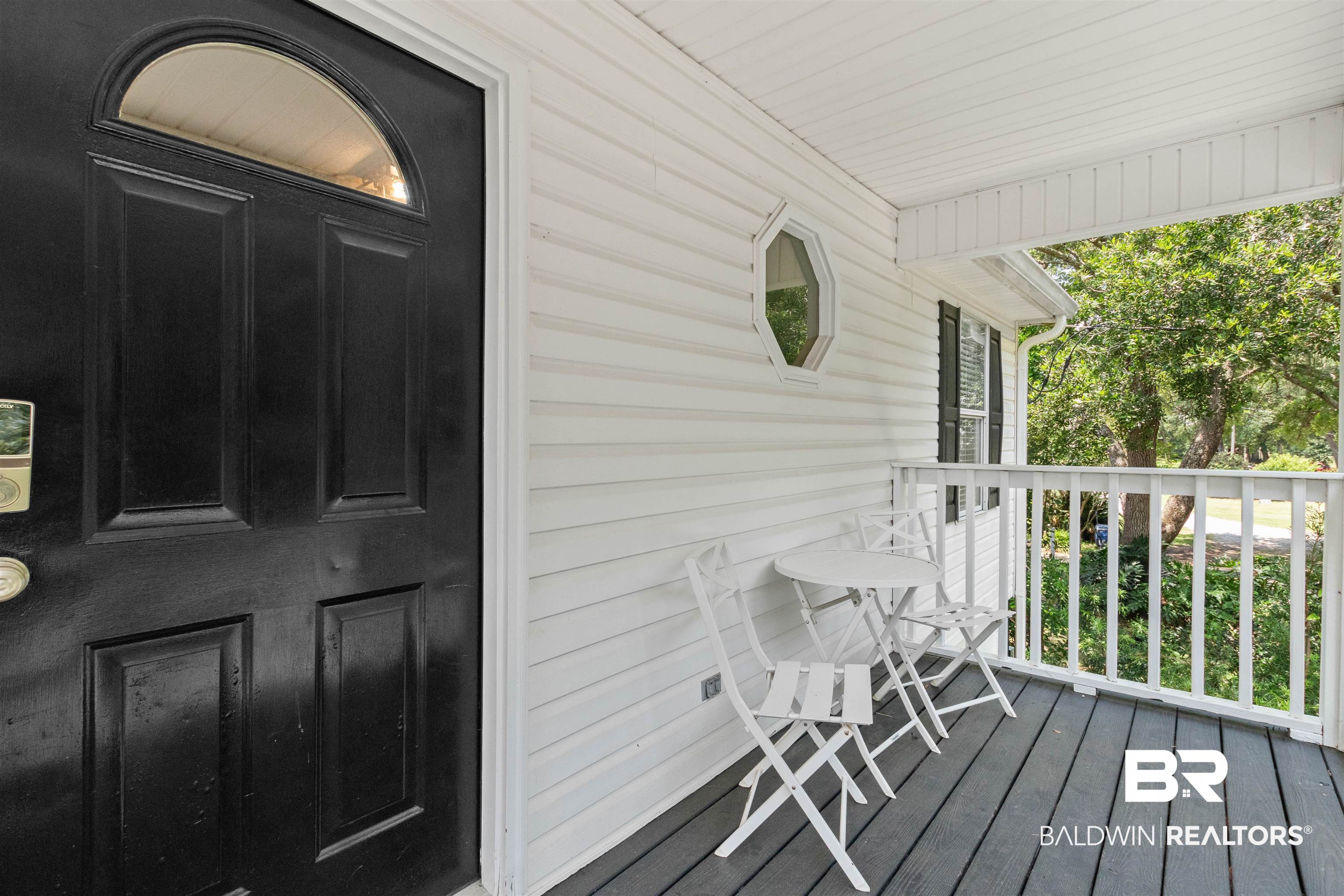 9581 South Bay Street Foley, AL 36535 - Photo 8 of 44 Inviting front porch featuring a dark wood-finish door with an arched transom, horizontal white siding, a white railing, and dark wood-finish flooring