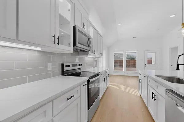 a kitchen with stainless steel appliances a sink stove and cabinets