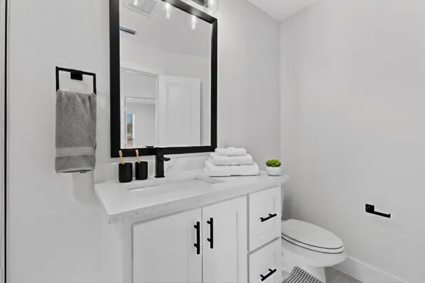 a bathroom with a granite countertop toilet sink and mirror