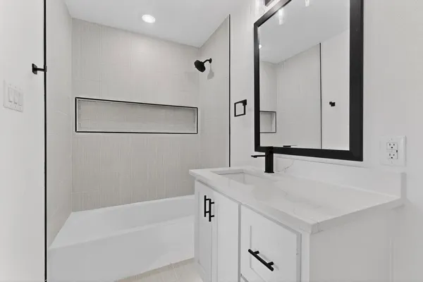 a bathroom with a granite countertop sink mirror and a bathtub