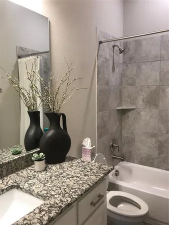 a bathroom with a granite countertop sink a toilet and bathtub