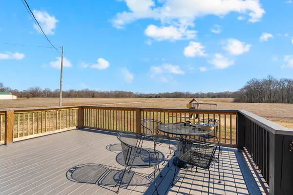 a view of a deck with wooden floor and fence with a barbeque