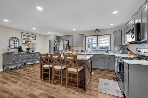 a kitchen with stainless steel appliances a refrigerator a stove a sink a dining table and chairs