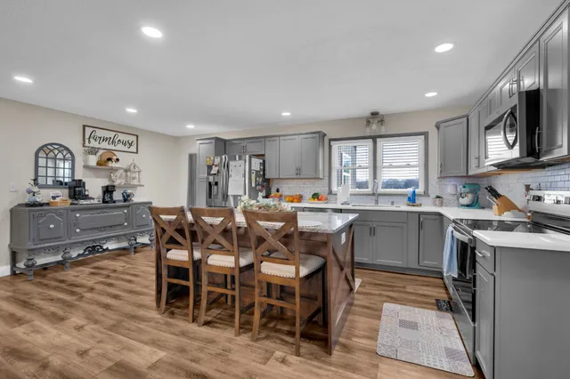 a kitchen with stainless steel appliances a refrigerator a stove a sink a dining table and chairs