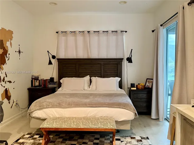 a bed sitting in a bedroom next to a window with furniture