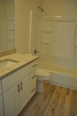 a bathroom with a granite countertop toilet a sink and a bathtub