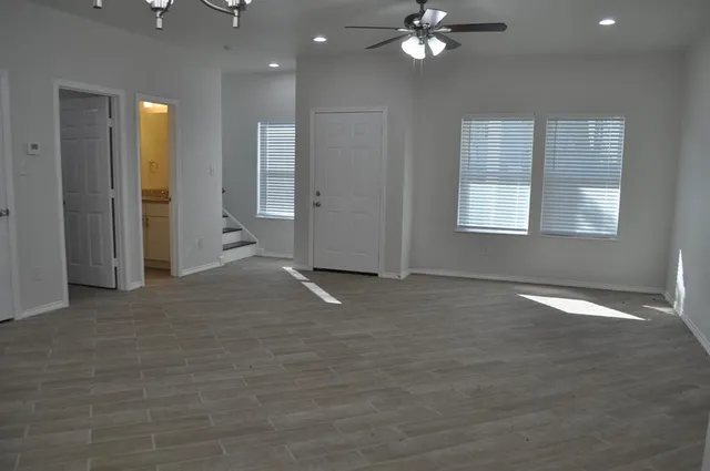 an empty room with chandelier fan and windows