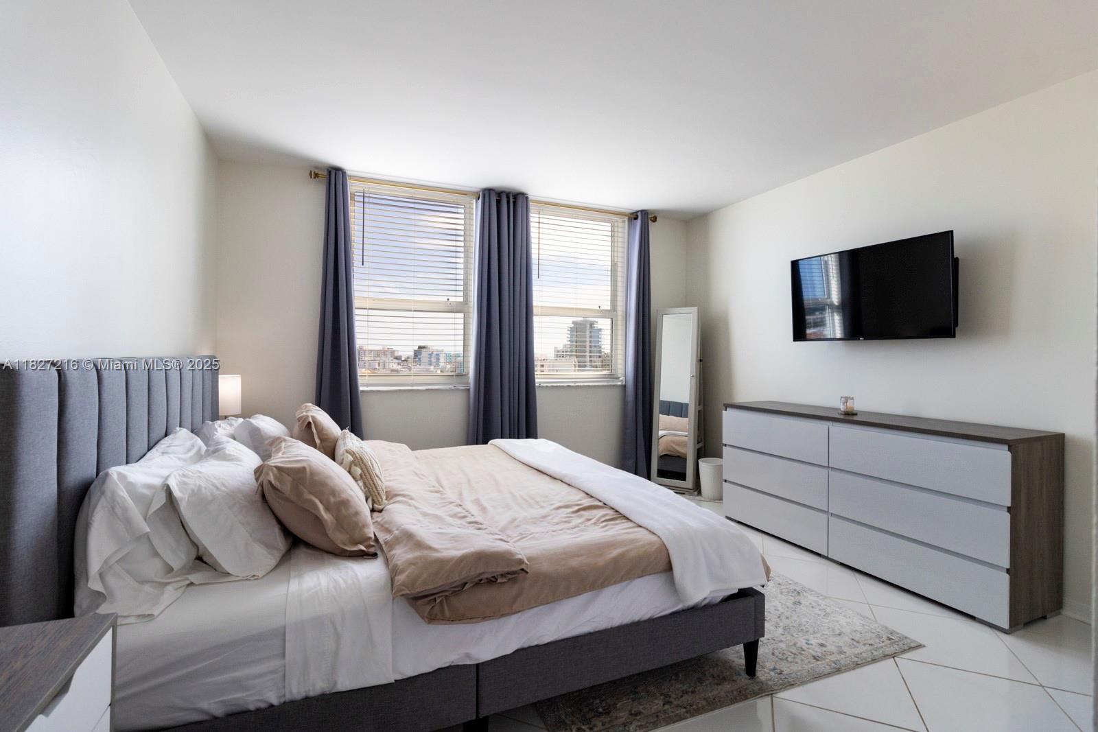 90 Alton Road, Unit 1005 Miami Beach, FL 33139 - Photo 11 of 22 a bedroom with a bed and a flat screen tv