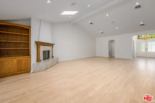 a view of empty room with wooden floor and fireplace