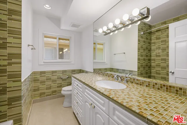 a bathroom with a granite countertop sink a mirror a glass door and shower