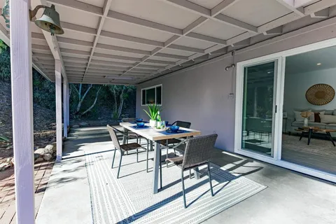 a patio with a table and chairs and potted plants