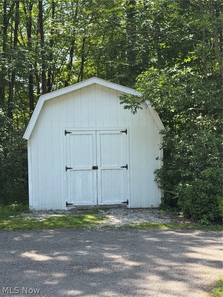 8201 Orchard Road Painesville, OH 44077 - Photo 44 of 45 White barn-style shed featuring vertical paneling and double doors with black hardware