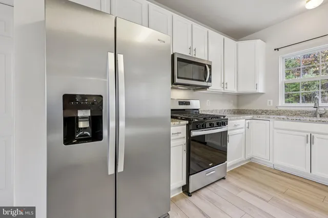 a kitchen with stainless steel appliances granite countertop a refrigerator and a stove top oven