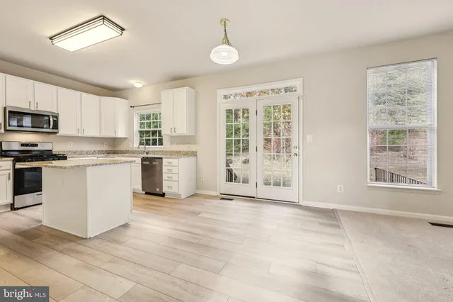 a kitchen with stainless steel appliances granite countertop a stove a sink dishwasher and a refrigerator with wooden floor