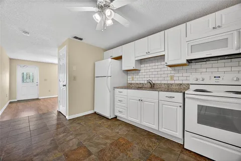 a kitchen with granite countertop white cabinets and white appliances