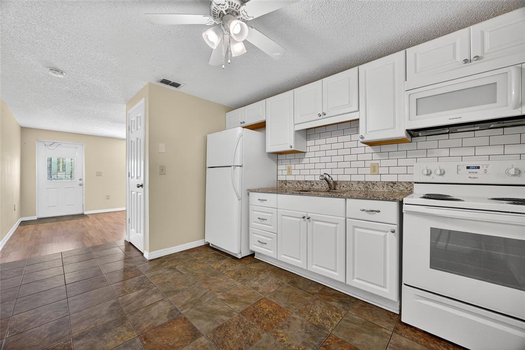 12337 Buffing Road, Unit A AND B Port Charlotte, FL 33981 - Photo 5 of 27 a kitchen with granite countertop white cabinets and white appliances