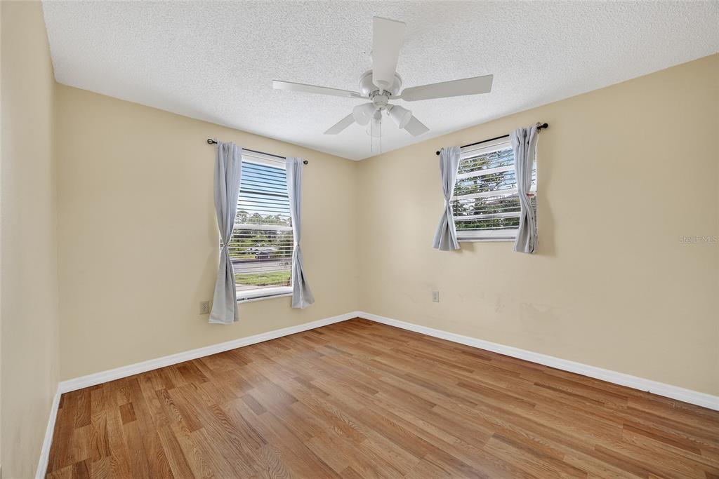 12337 Buffing Road, Unit A AND B Port Charlotte, FL 33981 - Photo 6 of 27 an empty room with wooden floor windows and fan
