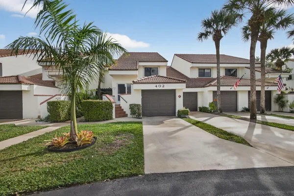 a view of a house with a yard and palm trees