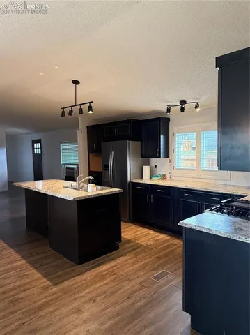 a large kitchen with kitchen island a sink dishwasher a stove and a refrigerator with wooden floor