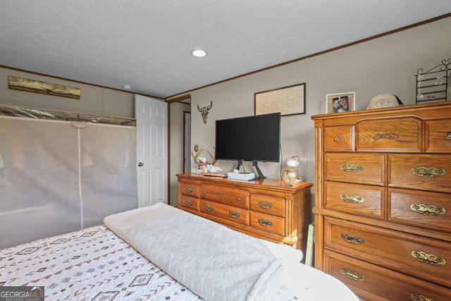223 Primrose Lane Baxley, GA 31513 - Photo 12 of 27 a room with a bed and a flat screen tv in a dresser